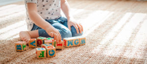 toddler playing with alphabet blocks on a rug