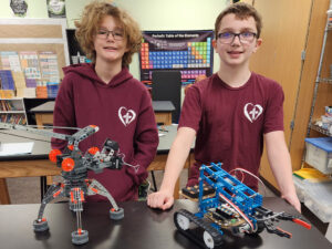 Two St. Michael Lutheran middle school students standing proudly in front of their robotics projects